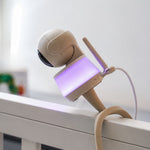 Luna Glow babyfoon camera met zacht paars nachtlampje op de rand van een babybedje